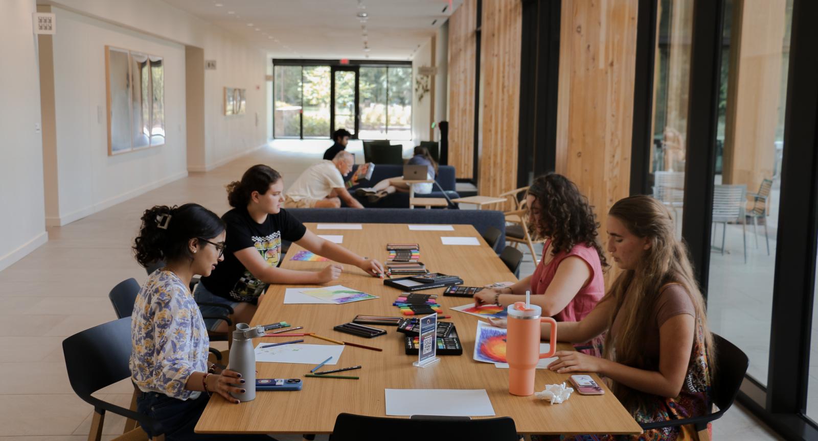 Four students painting in the Contemplative Commons first floor gallery. More students are further back in the hallway. 