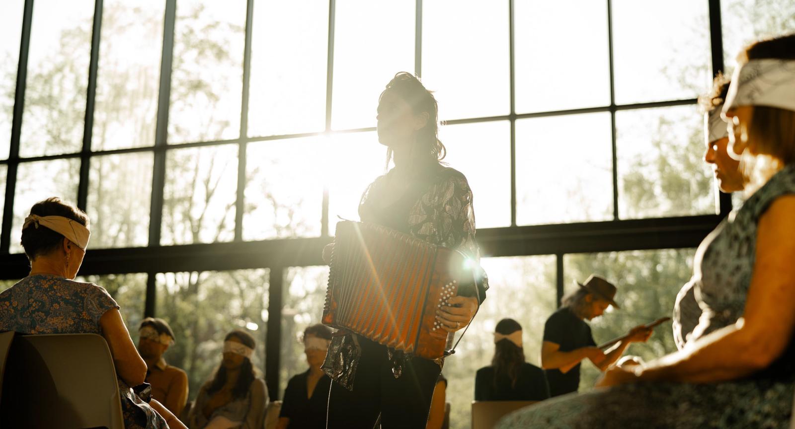Musician play accordian during a Golden Hour with participants blindfolded.