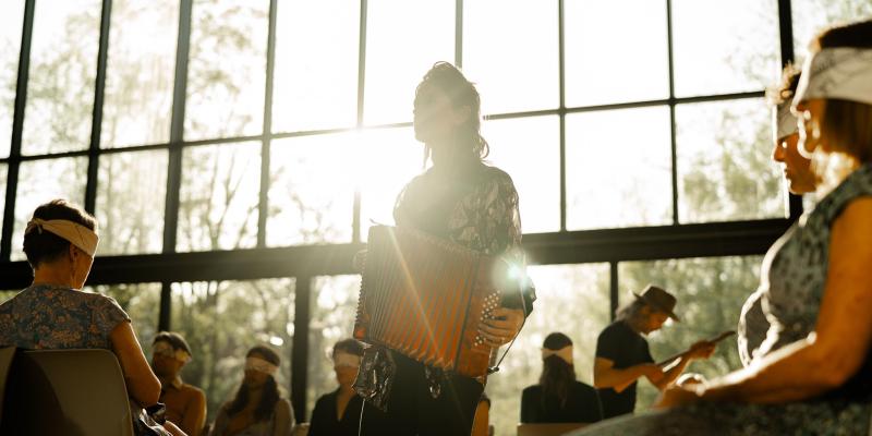 Musician play accordian during a Golden Hour with participants blindfolded.