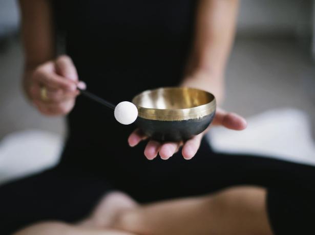 Close-up of a meditation bowl-bell being rung by a person in half-lotus posture