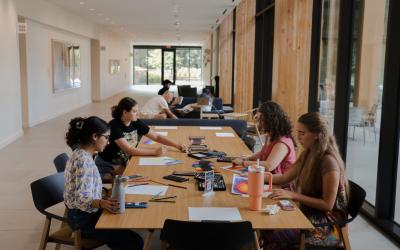 Four students painting in the Contemplative Commons first floor gallery. More students are further back in the hallway. 