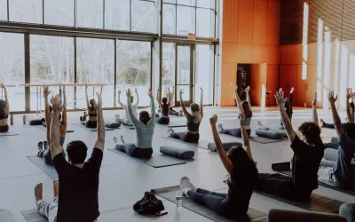 Students on yoga mats with arms raised in the Contemplative Commons