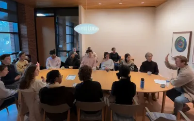 Students around a table discussing yoga with John Bultman