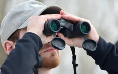 Close up of college student looking through binoculars outside