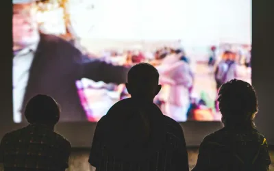 Three silhouettes of people watching a movie