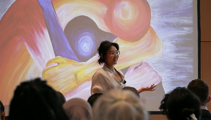 A woman giving a lecture with a projected piece of art in the background