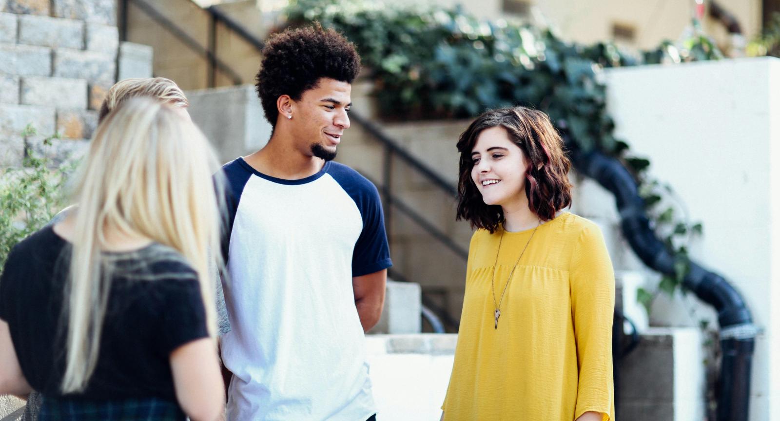 A group of three students stands in the lobby of a building and talk