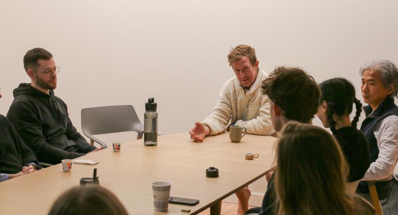 John Bultman with several people around a table. Cups of chai are on the table.