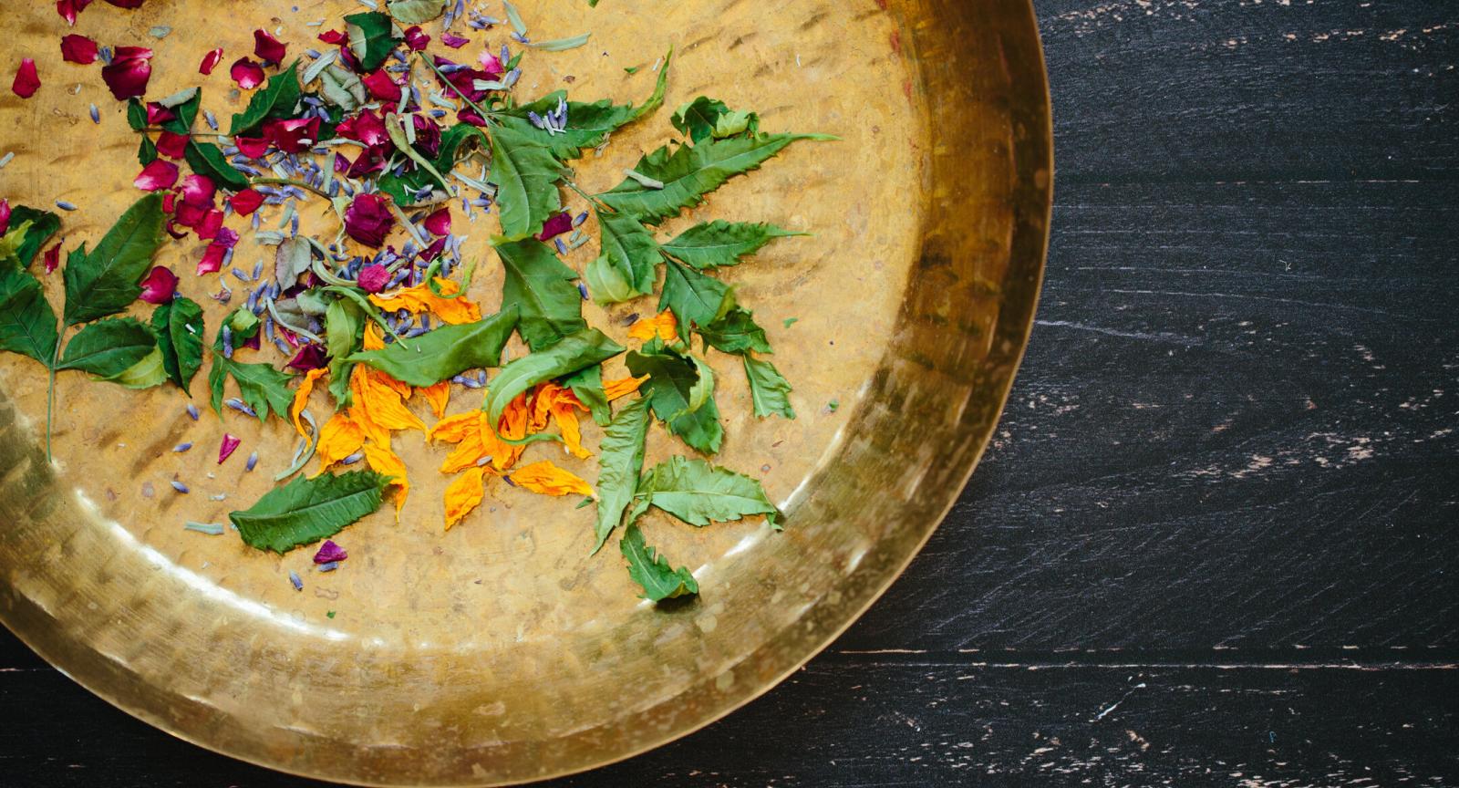 A brass platter sprinkled with flowers and petals