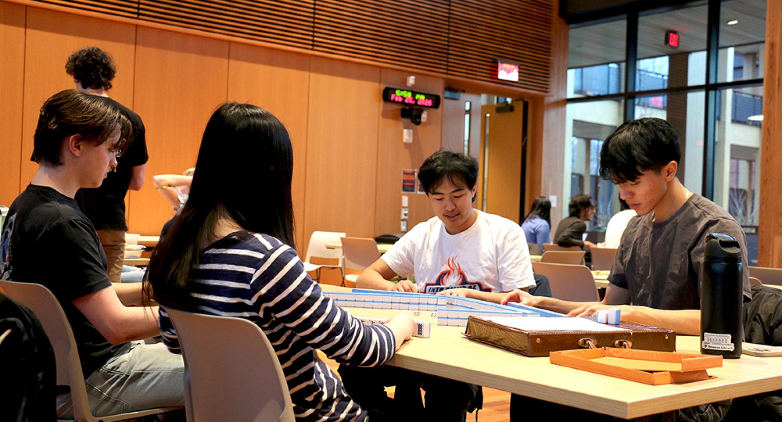 Four people playing Mahjong at a table