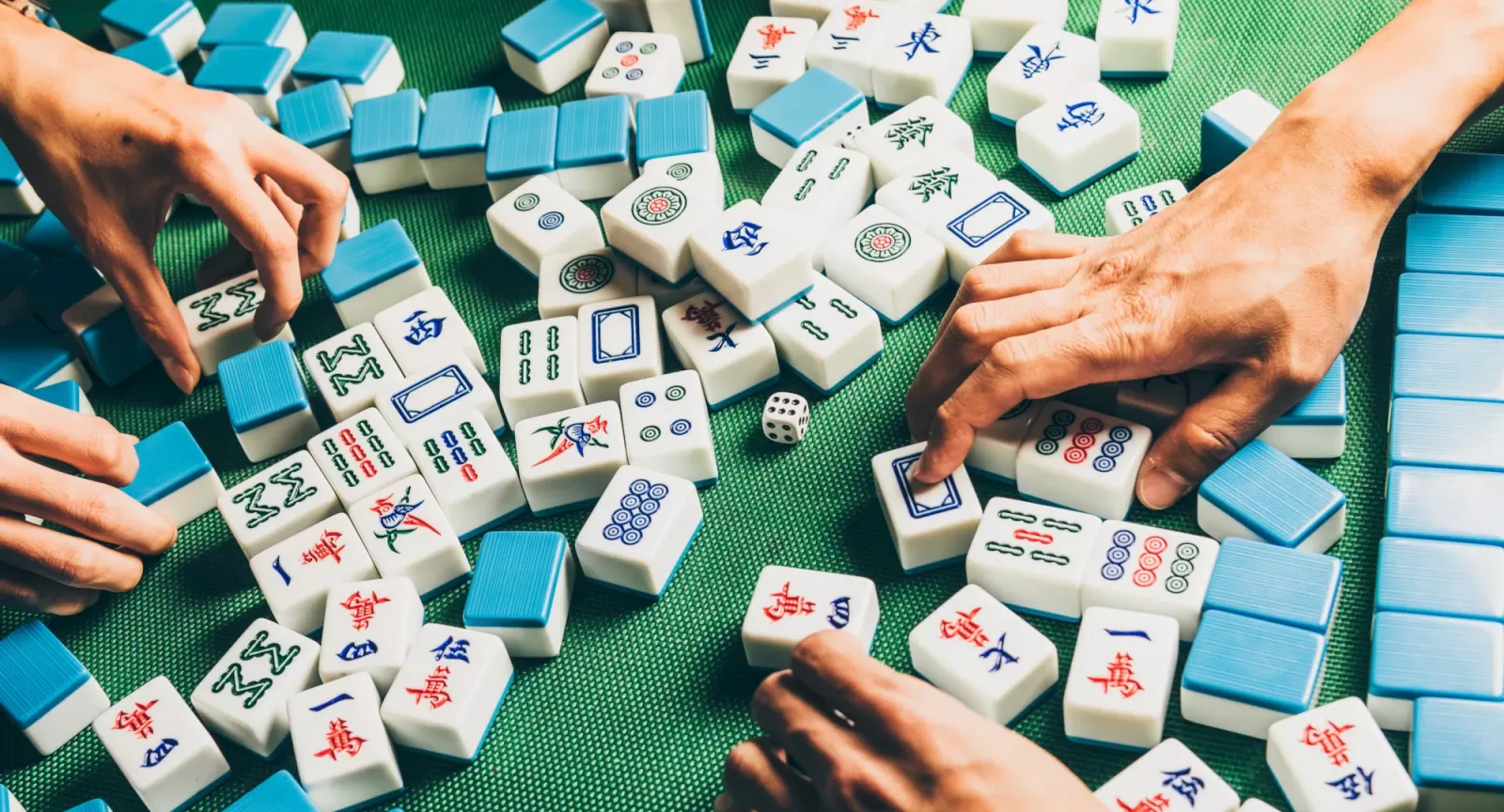 Majong tiles on a table with hands reaching for them