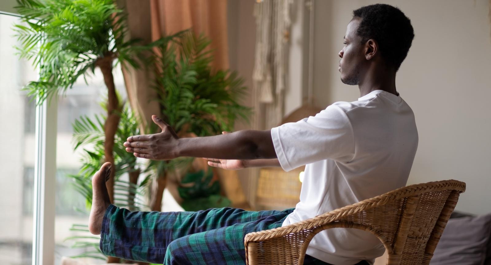 Person doing chair yoga in their home by a window