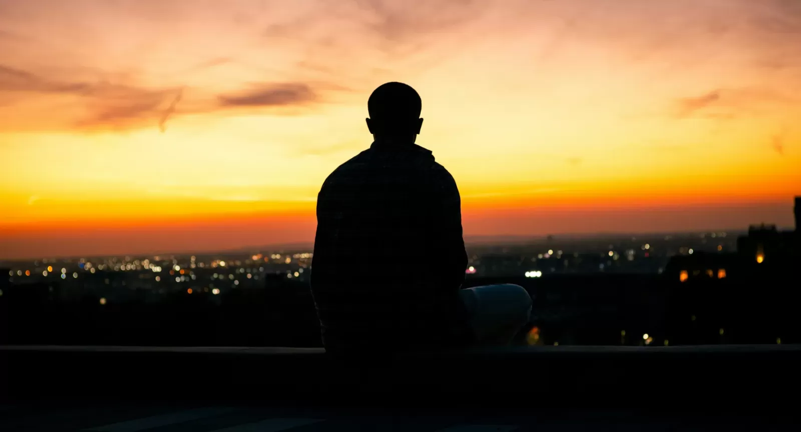 Silhouette of a meditator overlooking a city at sunset (Photo by: Jaykumar Bherwan)