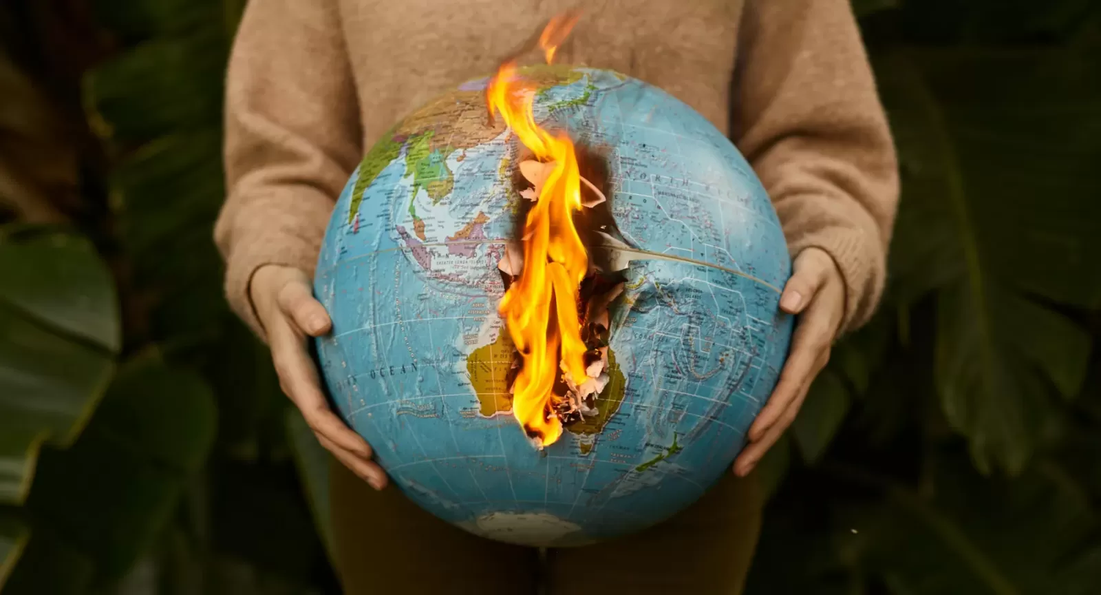 Woman holding a burning globe with dense vegetation in the background
