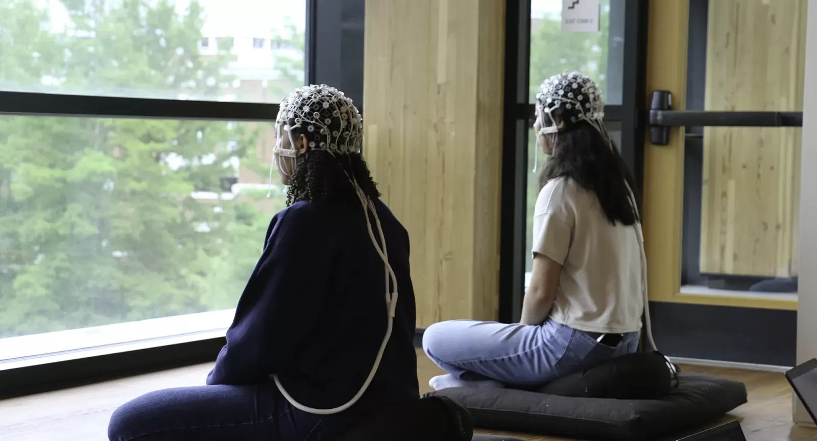 Two meditating subjects face a window in the Contemplative Commons and hooked up to EEG sensors