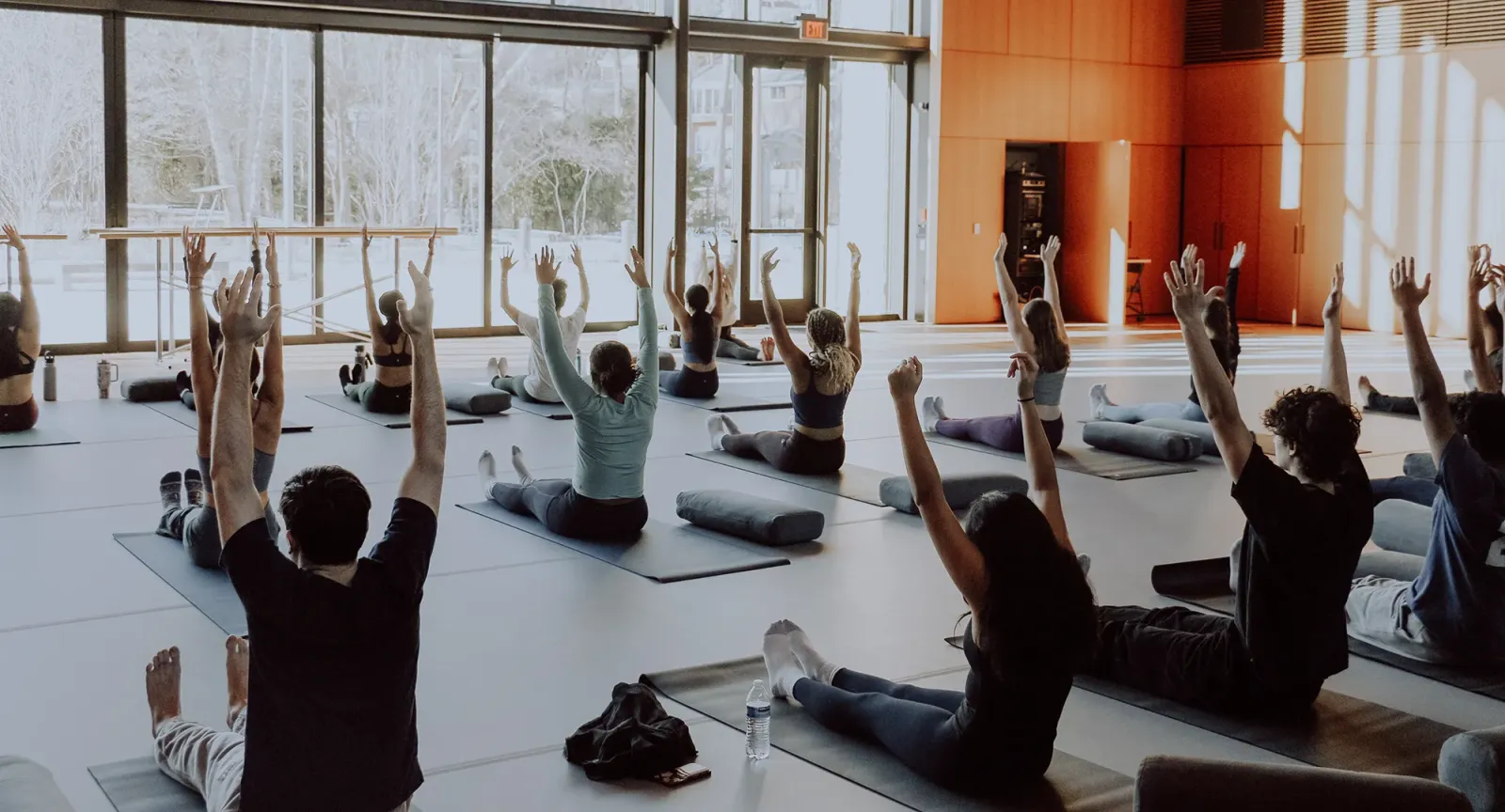 Students on yoga mats with arms raised in the Contemplative Commons