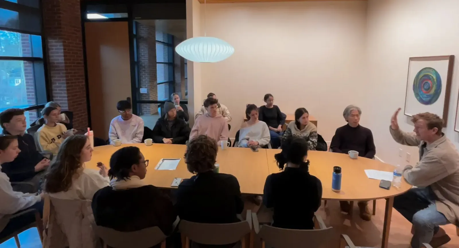 Students around a table discussing yoga with John Bultman