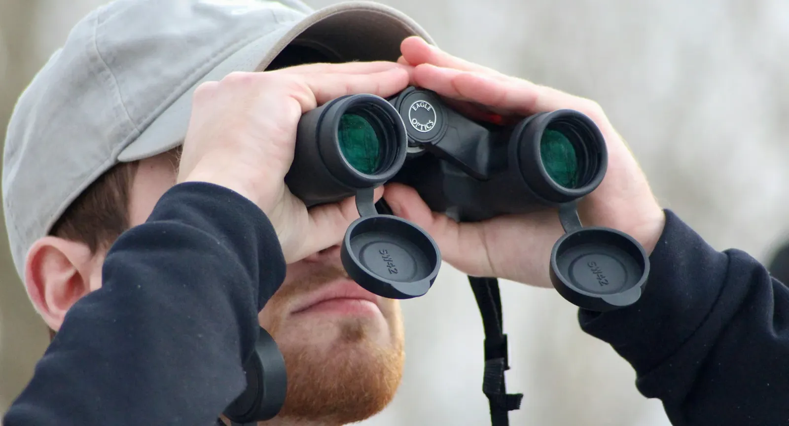 Close up of college student looking through binoculars outside