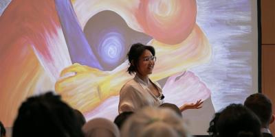 A woman giving a lecture with a projected piece of art in the background