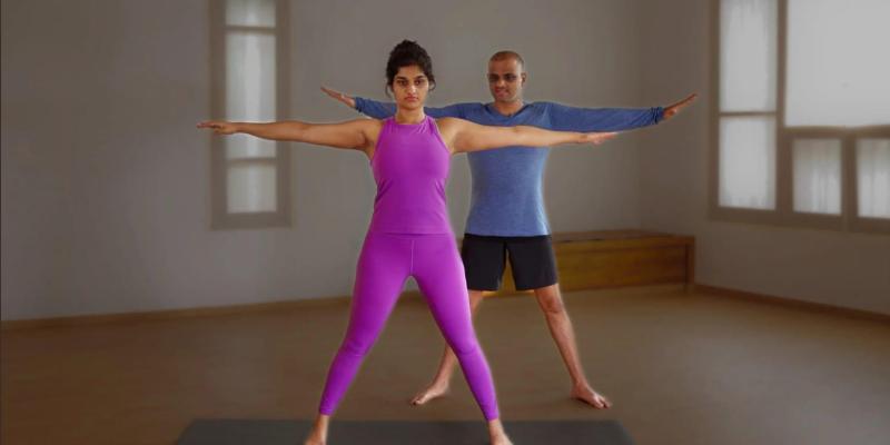 A woman in pink and a man in blue doing yoga in a studio