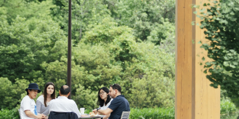 People sitting around a table in the Commons courtyard holding a pensive discussion