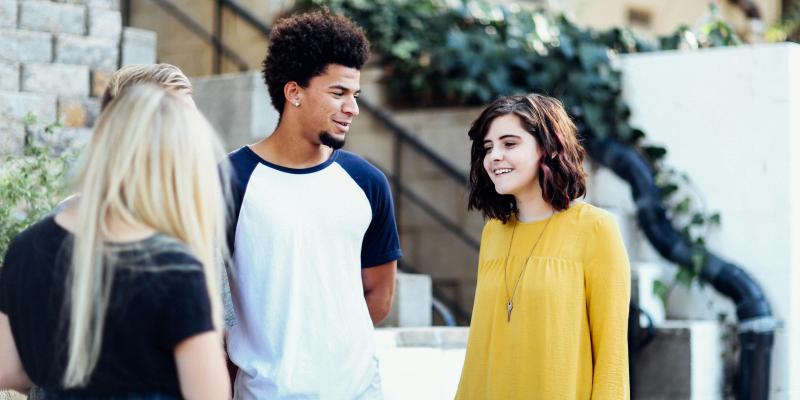 A group of three students stands in the lobby of a building and talk
