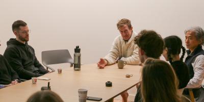 John Bultman with several people around a table. Cups of chai are on the table.
