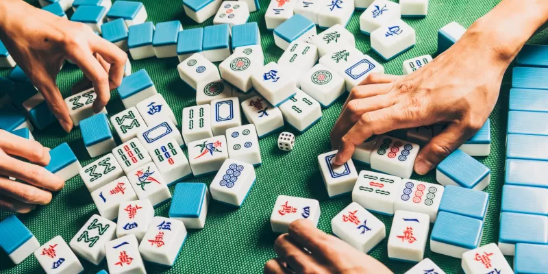 Majong tiles on a table with hands reaching for them