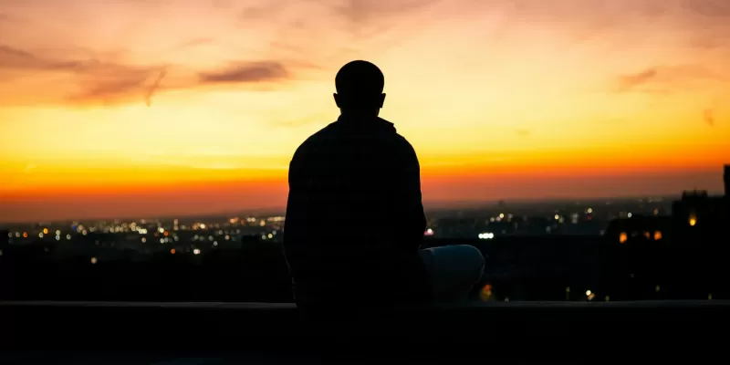 Silhouette of a meditator overlooking a city at sunset (Photo by: Jaykumar Bherwan)