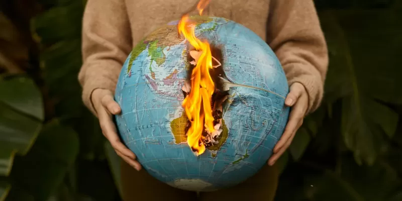 Woman holding a burning globe with dense vegetation in the background