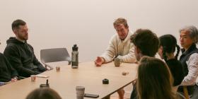 John Bultman with several people around a table. Cups of chai are on the table.