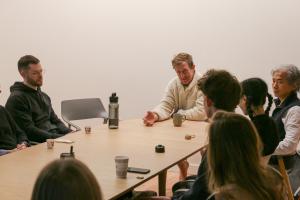 John Bultman with several people around a table. Cups of chai are on the table. 
