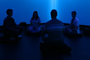 Four people sitting on cushions experiencing the exhibit in the Conservatory