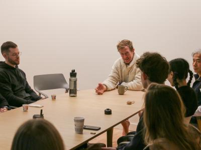 John Bultman with several people around a table. Cups of chai are on the table. 