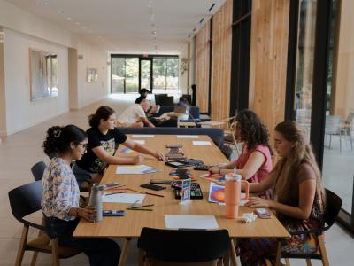 Four students painting in the Contemplative Commons first floor gallery. More students are further back in the hallway. 