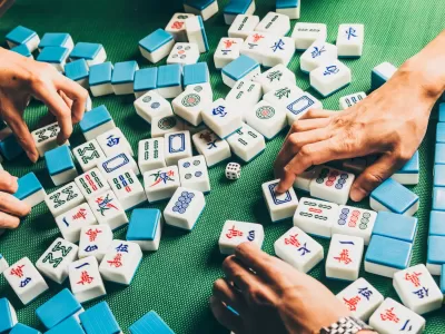 Majong tiles on a table with hands reaching for them