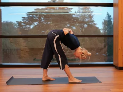 Nora Brookfield demonstrating a yoga pose before a window at the Contemplative Commons