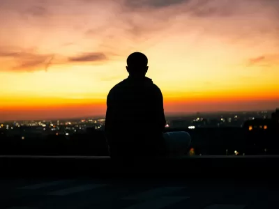Silhouette of a meditator overlooking a city at sunset (Photo by: Jaykumar Bherwan)