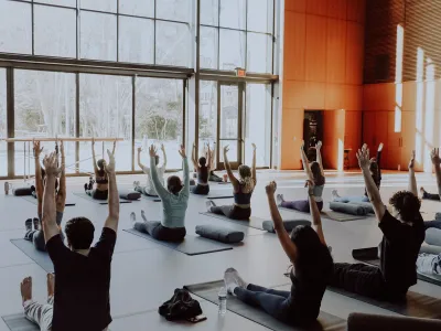 Students on yoga mats with arms raised in the Contemplative Commons