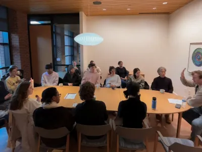 Students around a table discussing yoga with John Bultman