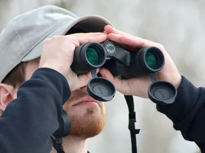 Close up of college student looking through binoculars outside