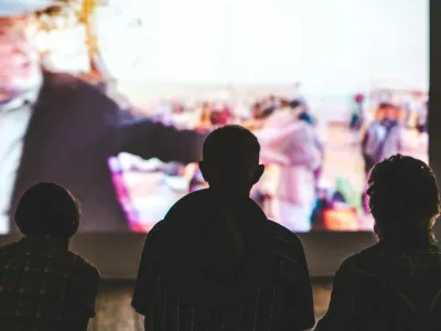 Three silhouettes of people watching a movie